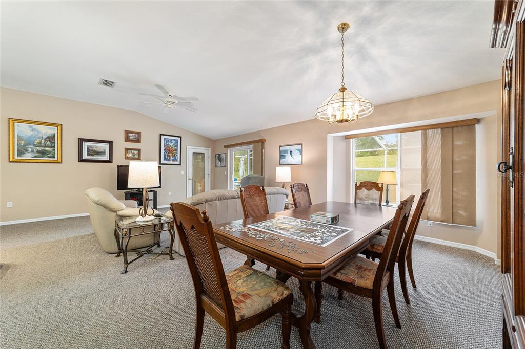 A dining area with a wooden table and chairs sits in front of a living room — 11534 SW 74TH COURT, OCALA, FL