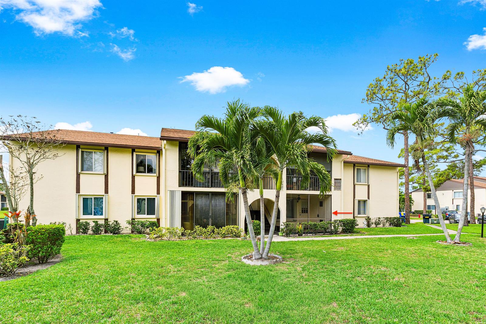 A two-story apartment building with a beige exterior, brown roof, and a screened-in patio — 3560 Pine Tree Court # 1, FL 33463, FL