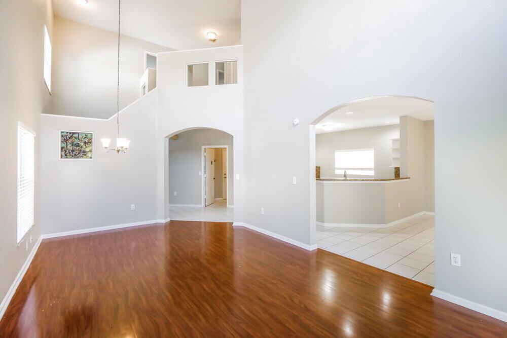 A spacious living room with hardwood floors, high ceilings, and an arched entryway to the kitchen — CORAL SPRINGS, FL