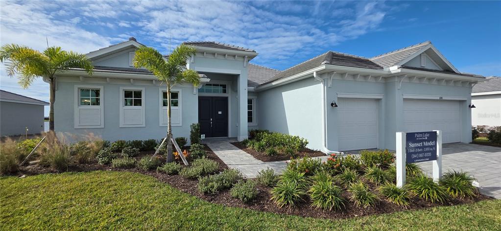 A light blue single-story house features a three-car garage and a paved walkway — 8140 SHORE LAKE DRIVE, ENGLEWOOD, FL