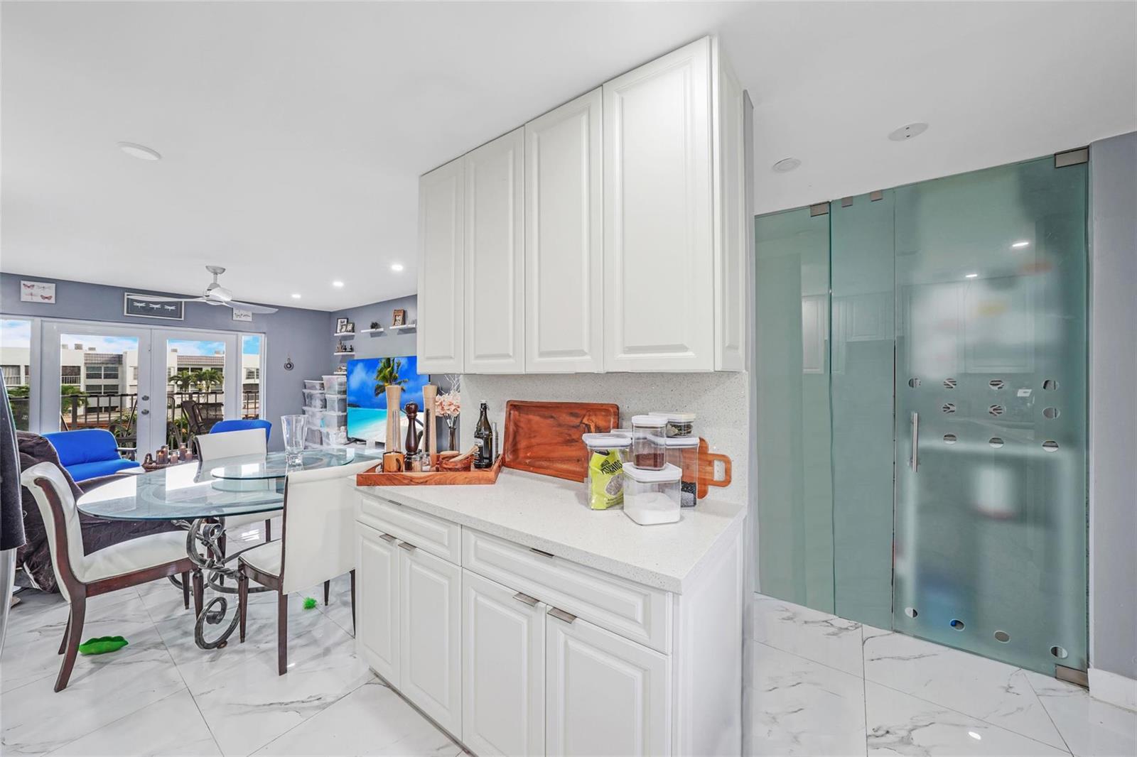 A kitchen area features white cabinets, quartz countertops, and a large frosted glass door — 6650 Royal Palm Boulevard # 306c, Pompano Beach FL 33063, POMPANO BEACH, FL