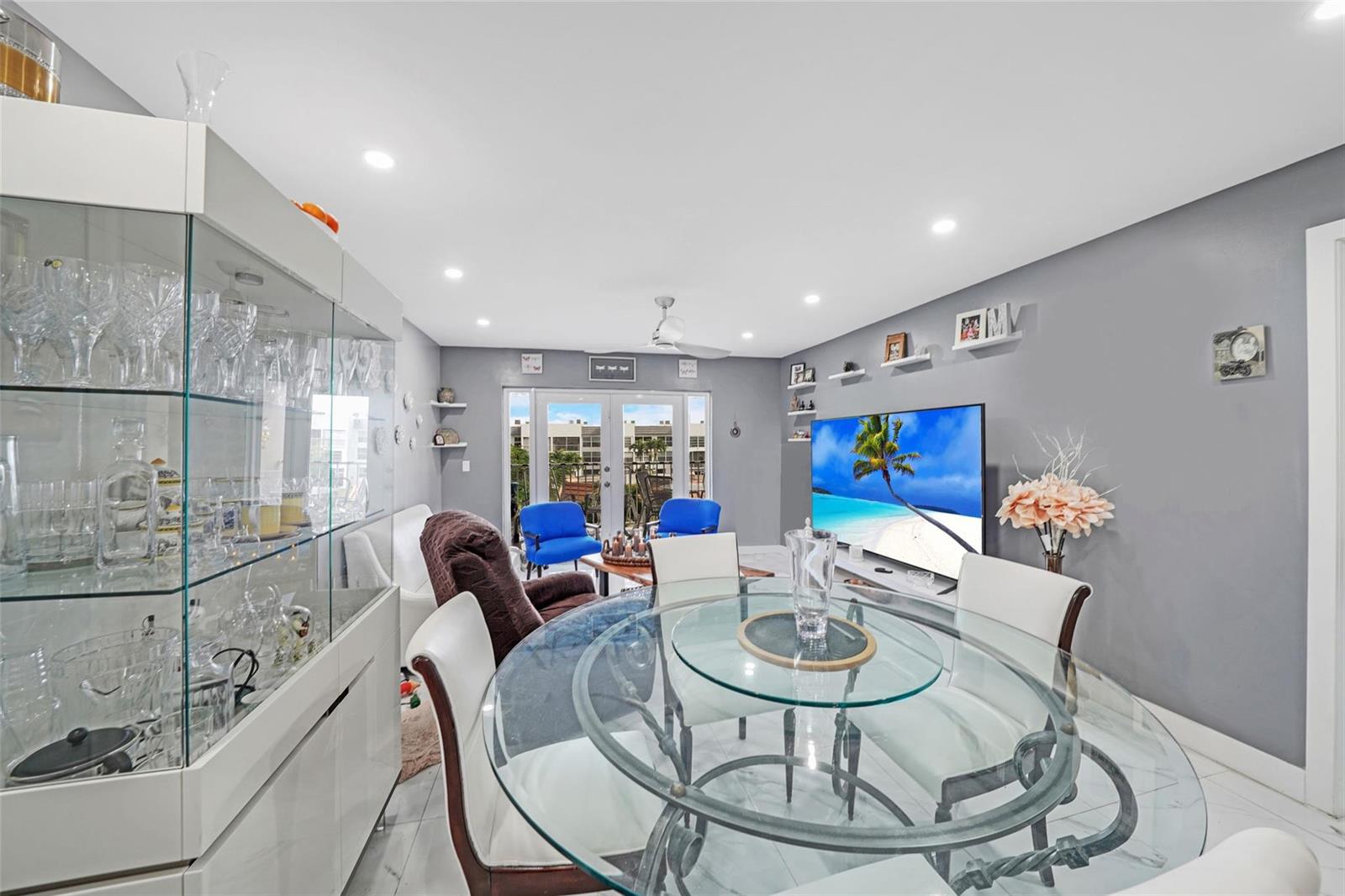 A dining area with a glass table and display cabinet opens to a living room — 6650 Royal Palm Boulevard # 306c, Pompano Beach FL 33063, POMPANO BEACH, FL