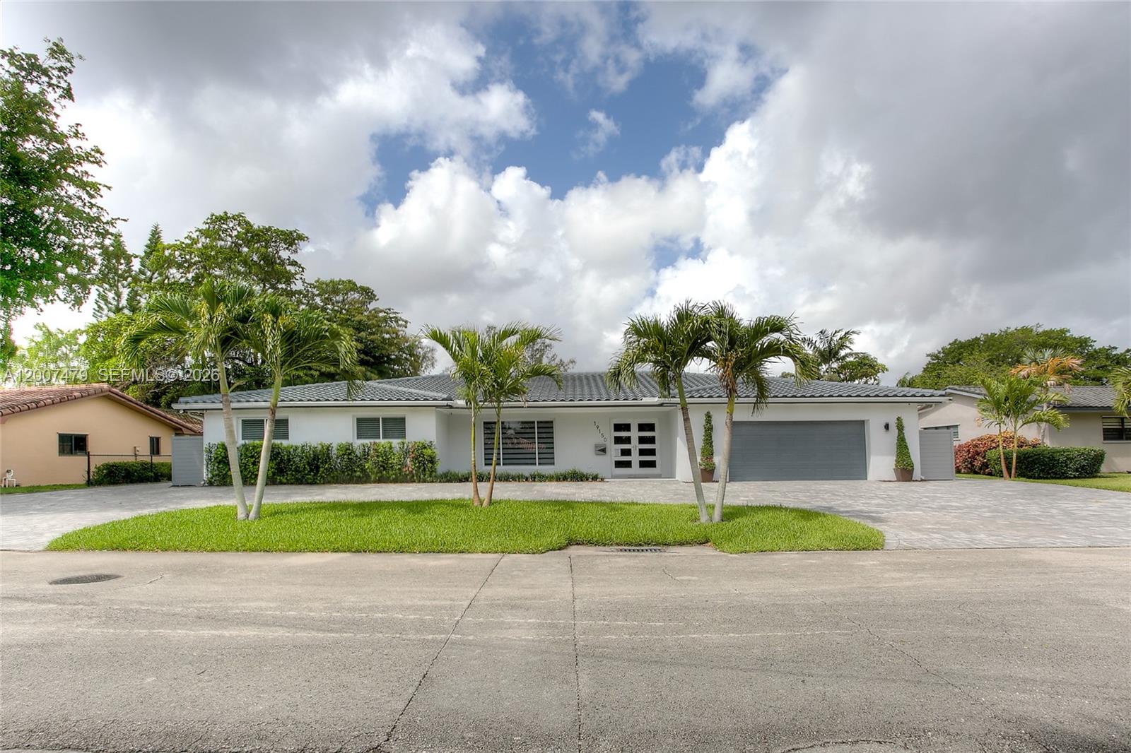A single-story white house with a gray tiled roof, palm trees, and a paved driveway — 19150 S Saint Andrews Dr, Hialeah FL 33015, HIALEAH, FL