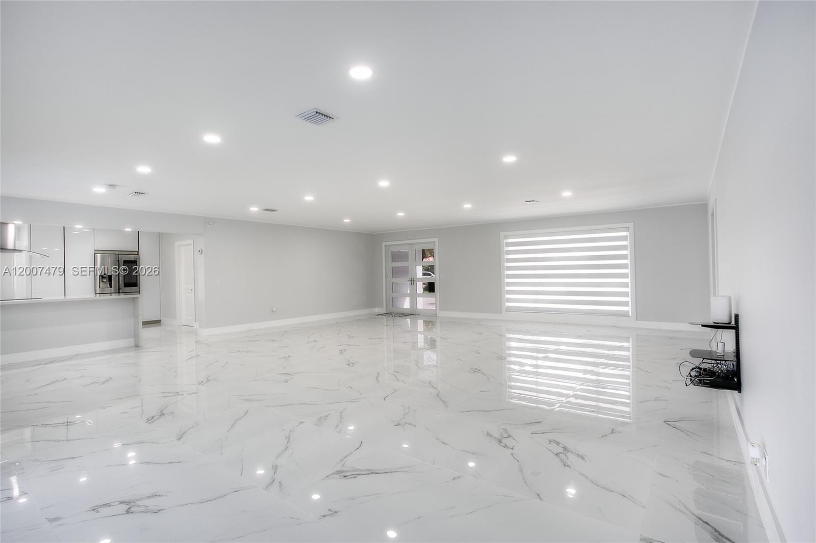 A spacious, minimalist living area features white marble tile flooring and recessed ceiling lighting — 19150 S Saint Andrews Dr, Hialeah FL 33015, HIALEAH, FL