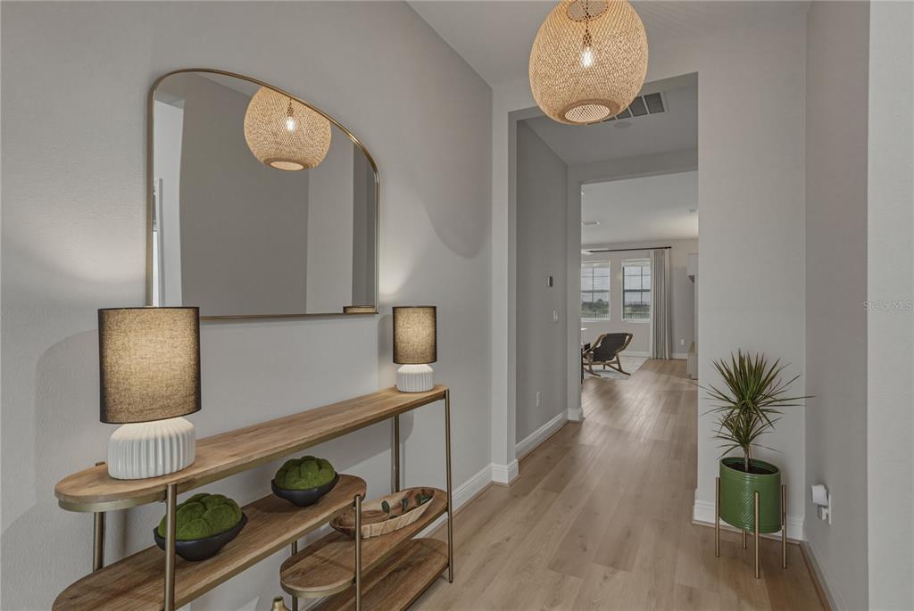 A hallway features a wooden console table with lamps, a mirror, and a potted plant — 10368 FIELDSTONE MYRTLE WAY, SAN ANTONIO, FL