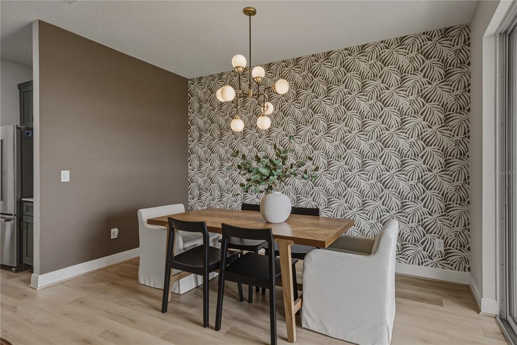 A dining area features a wooden table, mixed seating, and a patterned accent wall — 10368 FIELDSTONE MYRTLE WAY, SAN ANTONIO, FL
