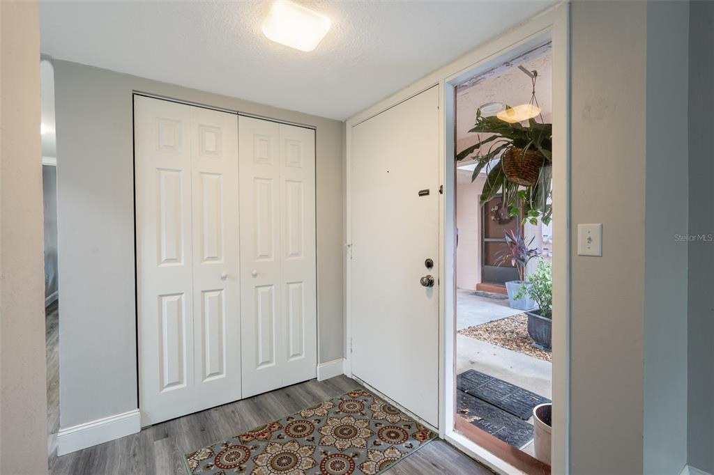 An entryway features a white door, a double-door closet, and gray wood-look flooring — 100 SWEETGUM WOODS COURT UNIT 10C, DELTONA, FL