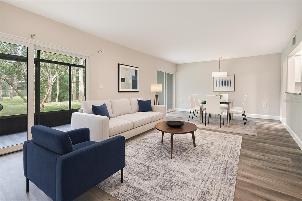 A living and dining area with light wood floors, a white sofa, and a blue armchair — 100 SWEETGUM WOODS COURT UNIT 10C, DELTONA, FL