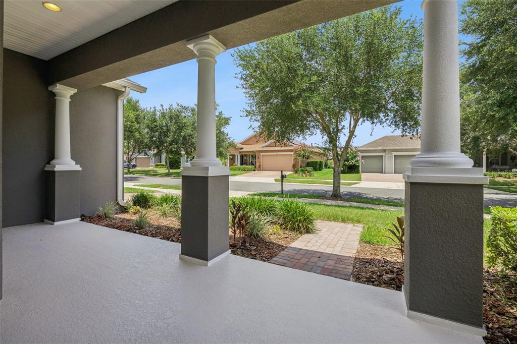 A covered front porch with white columns overlooks a suburban street and neighboring houses — 228 BAYOU BEND ROAD, GROVELAND, FL