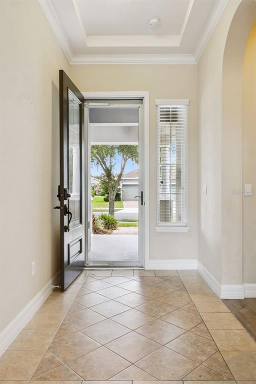 An entryway with a tiled floor, a tray ceiling, and an open door to outside — 228 BAYOU BEND ROAD, GROVELAND, FL