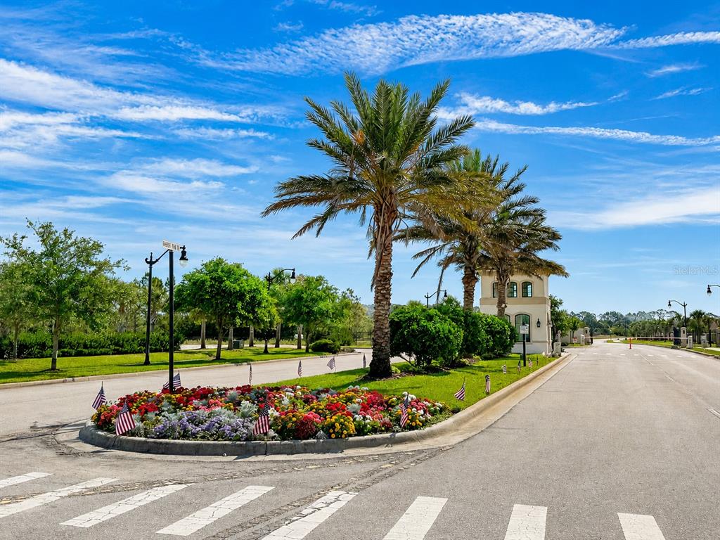 A landscaped traffic island with palm trees and flowers sits at a gated community entrance — 1 MENORCA WAY, PALM COAST, FL