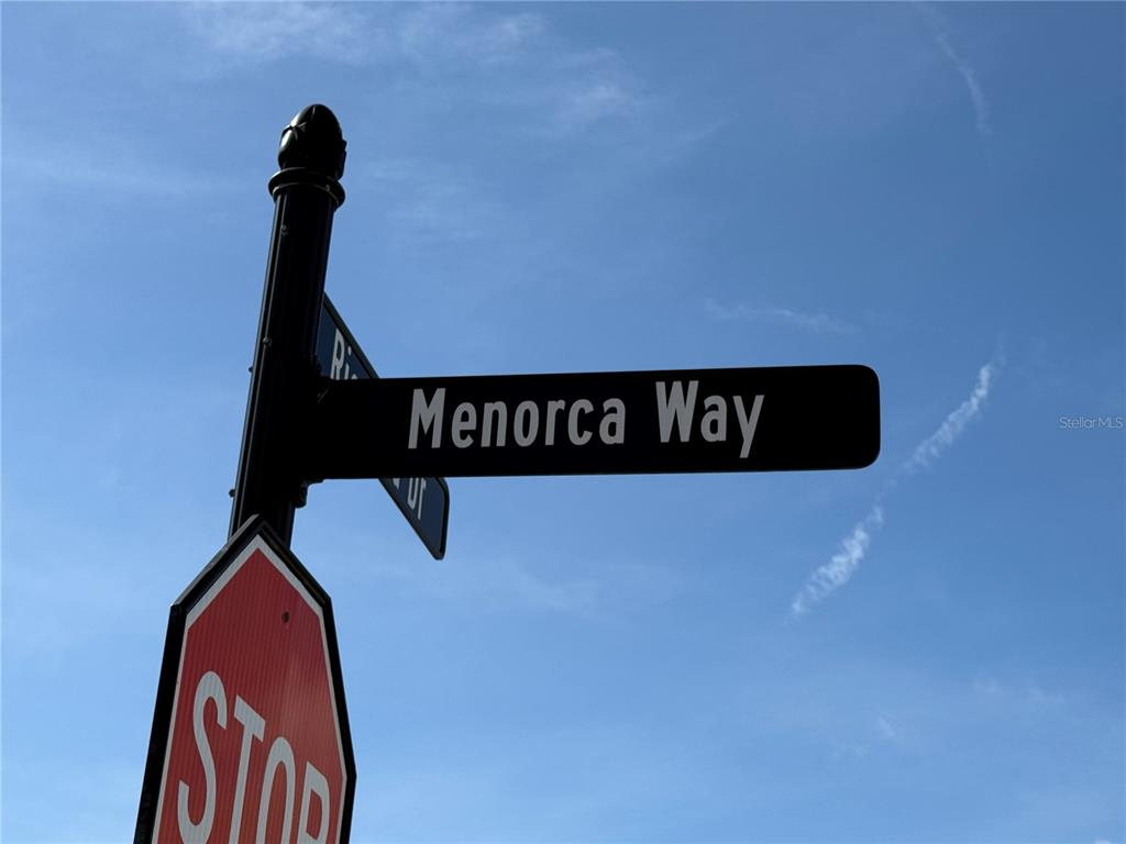 A street sign for Menorca Way is mounted above a stop sign against a blue sky — 1 MENORCA WAY, PALM COAST, FL