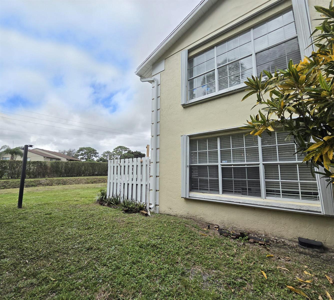 The exterior of a two-story beige house features white window frames and a white fence — 222 Foxtail Drive # I, FL 33415, FL