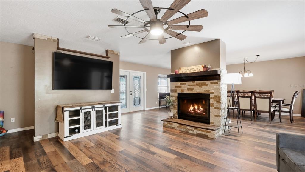 A living room features a stone fireplace, a wall-mounted television, and wood-look flooring — 12092 S HYACINTH POINT, FLORAL CITY, FL