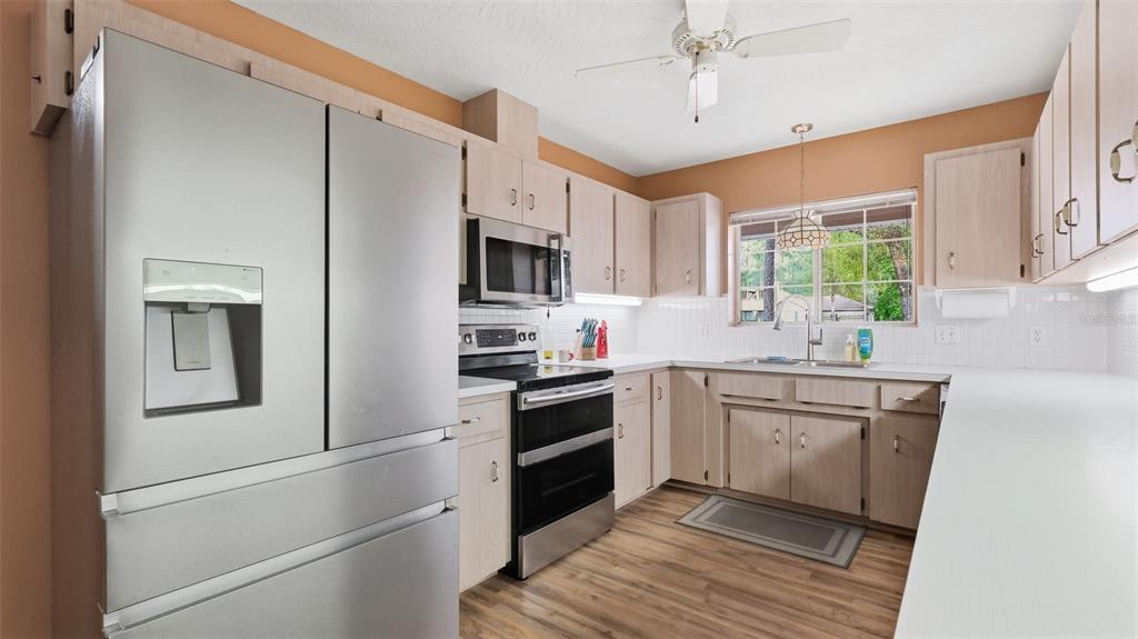 A kitchen features light wood cabinets, stainless steel appliances, white countertops, and wood-look flooring — 12092 S HYACINTH POINT, FLORAL CITY, FL