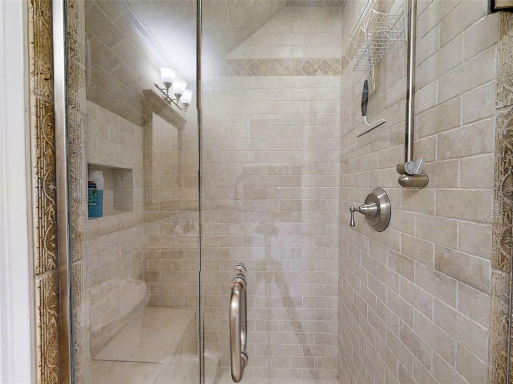 A tiled walk-in shower features a glass door, a built-in bench, and a recessed niche — 4849 SAXON DRIVE UNIT 2030, NEW SMYRNA BEACH, FL
