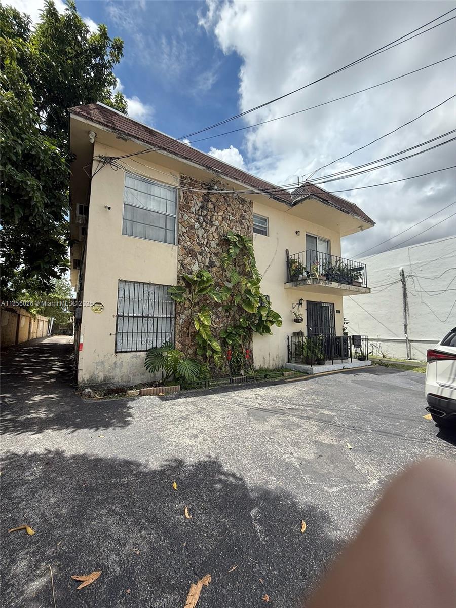 A two-story apartment building features a stone facade, a balcony, and a paved parking area — 1520 SW 1st St, Miami FL 33135, MIAMI, FL