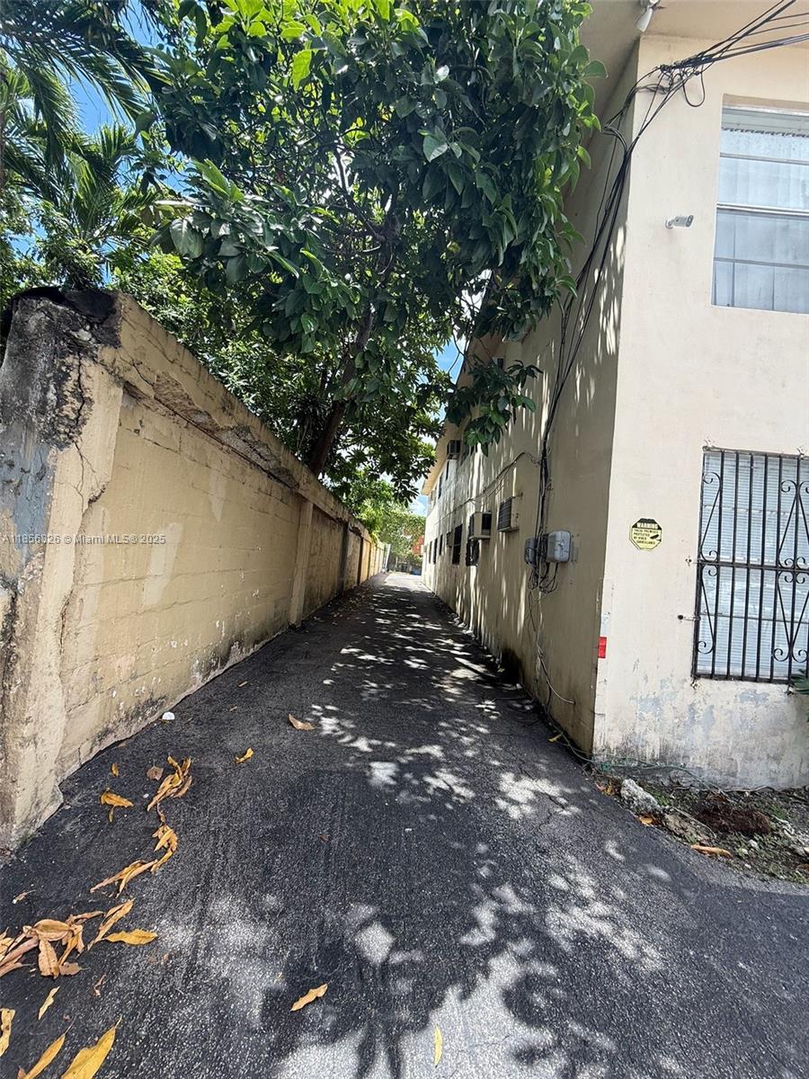 A narrow paved alleyway runs between a weathered concrete wall and a multi-story building — 1520 SW 1st St, Miami FL 33135, MIAMI, FL