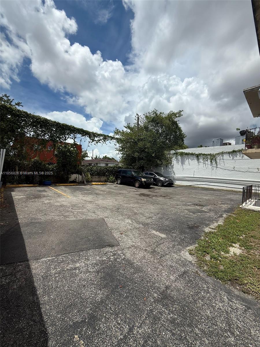 An outdoor asphalt parking lot features two parked vehicles and a white perimeter wall — 1520 SW 1st St, Miami FL 33135, MIAMI, FL