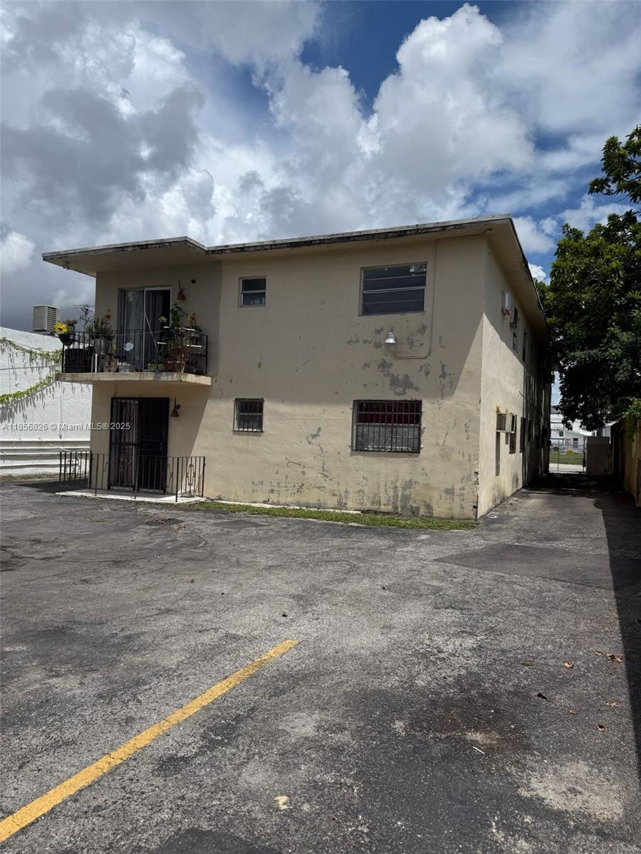 A two-story beige apartment building features a second-floor balcony and a paved parking lot — 1520 SW 1st St, Miami FL 33135, MIAMI, FL
