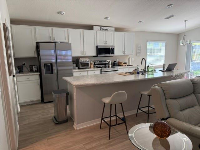 A kitchen features white cabinetry, stainless steel appliances, a large island, and light-colored flooring — 1552 FLEUR DRIVE, DAVENPORT, FL