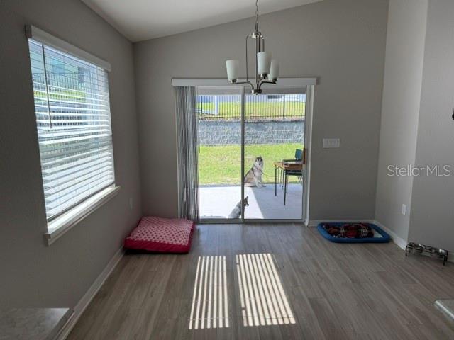 A dining area with wood-look flooring, a chandelier, and a sliding glass door to a yard — 1552 FLEUR DRIVE, DAVENPORT, FL