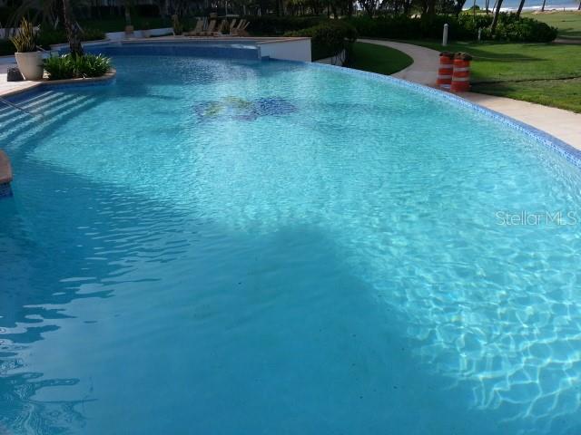 A curved swimming pool with a tiled sun mosaic sits beside a grassy lawn — 9000 RIO MAR  BOULEVARD UNIT 443, RIO GRANDE, PR