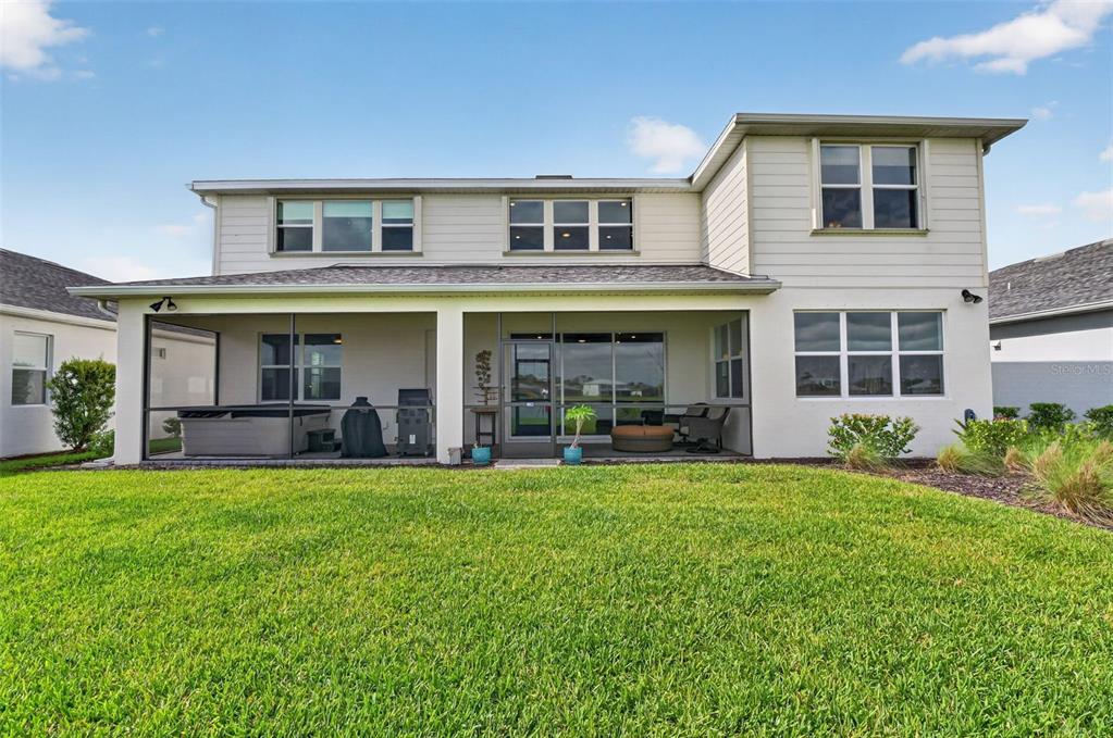 The exterior rear view of a two-story house features a screened-in patio and lawn — 42581 ATLAS DRIVE, PUNTA GORDA, FL