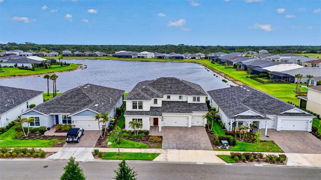 An aerial view shows three suburban houses situated along a lake with a paved street — 42581 ATLAS DRIVE, PUNTA GORDA, FL