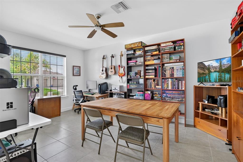 A home office and hobby room with a wooden table, shelving, guitars, and a television — 42581 ATLAS DRIVE, PUNTA GORDA, FL