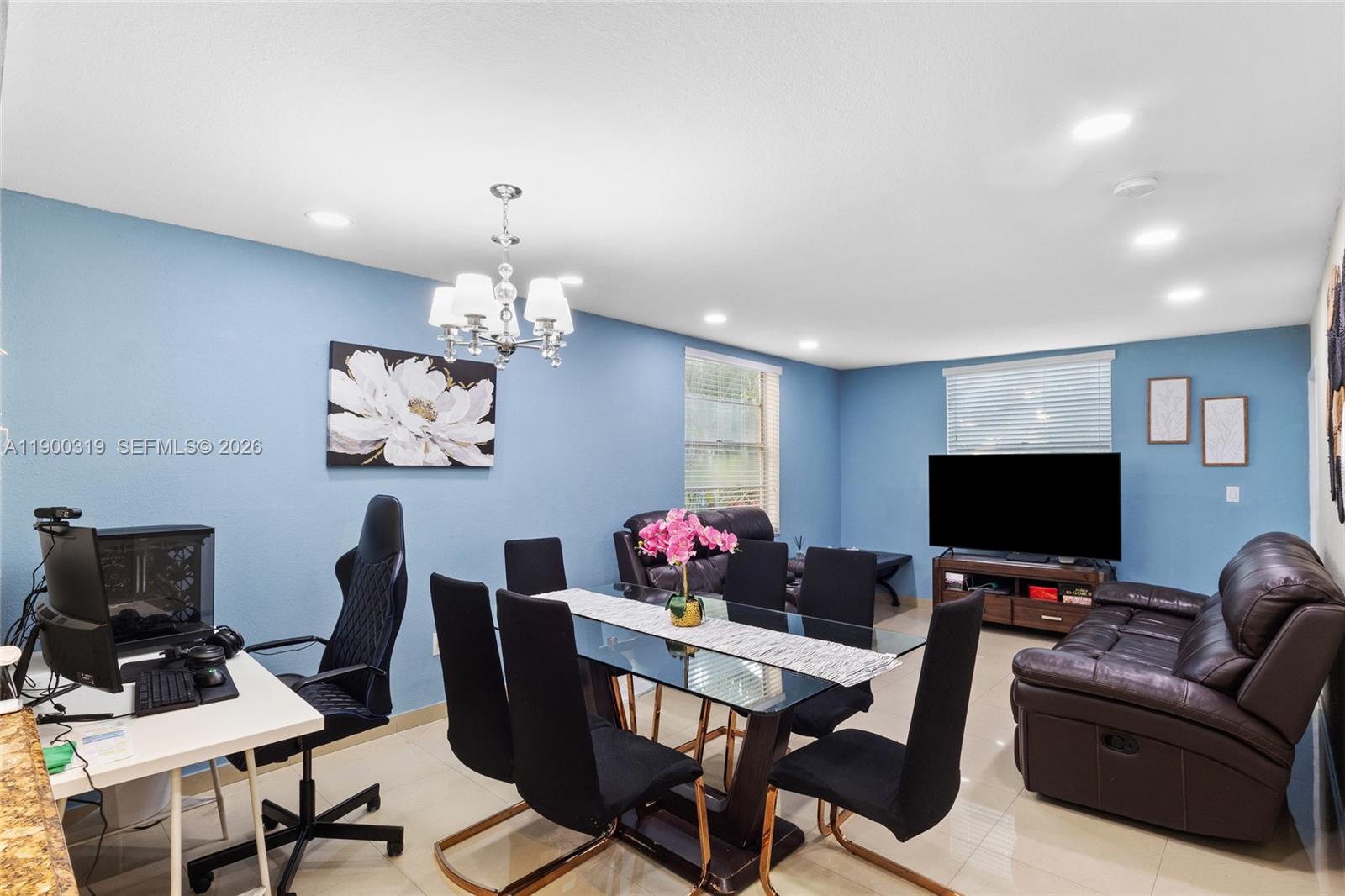 A dining room with blue walls features a glass table, black chairs, and a computer desk — 5665 W 20th Ave # 212, Hialeah FL 33012, HIALEAH, FL