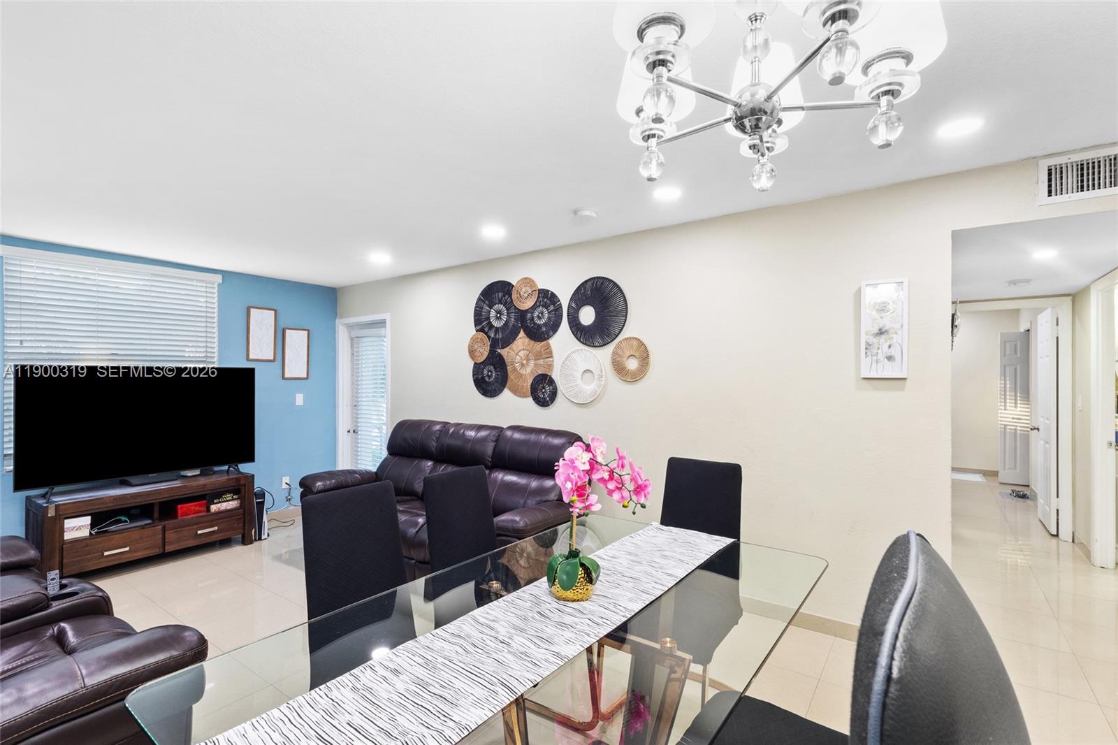 A dining area with a glass table sits in front of a living room space — 5665 W 20th Ave # 212, Hialeah FL 33012, HIALEAH, FL