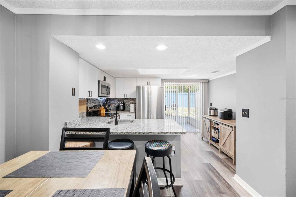 A kitchen with granite countertops, stainless steel appliances, and a breakfast bar with stools — 3350 FOX HUNT DRIVE, PALM HARBOR, FL