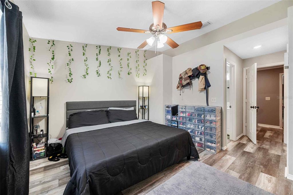 A bedroom features a bed with dark bedding, a ceiling fan, and clear shoe storage bins — 3350 FOX HUNT DRIVE, PALM HARBOR, FL