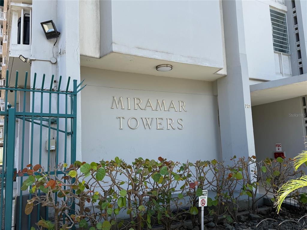 The exterior entrance of Miramar Towers features a white wall with building signage and landscaping — MIRAMAR TOWERS 721 HERNANDEZ ST. UNIT 12 D, SAN JUAN, PR