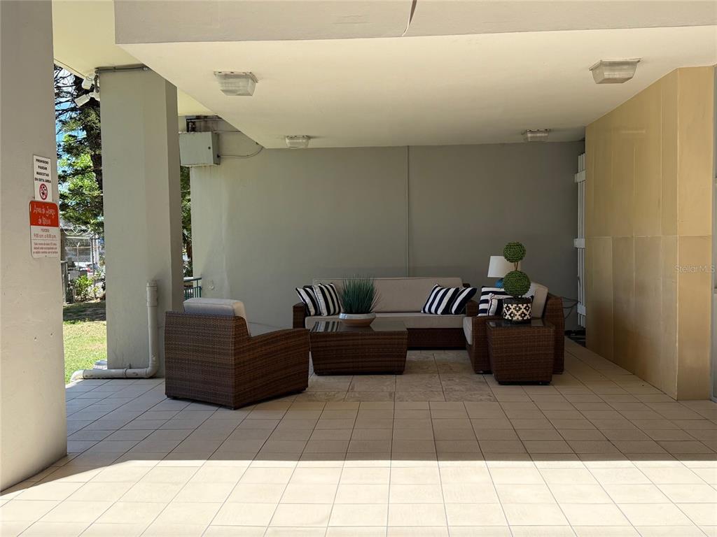 A covered outdoor patio features wicker furniture, a sofa, and light-colored floor tiles — MIRAMAR TOWERS 721 HERNANDEZ ST. UNIT 12 D, SAN JUAN, PR