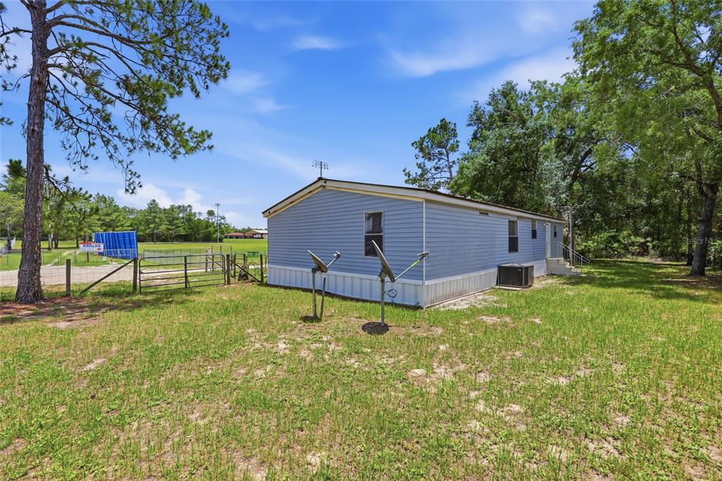 A blue mobile home sits on a grassy lot with two satellite dishes outside — 350 ISHIE AVENUE, BRONSON, FL