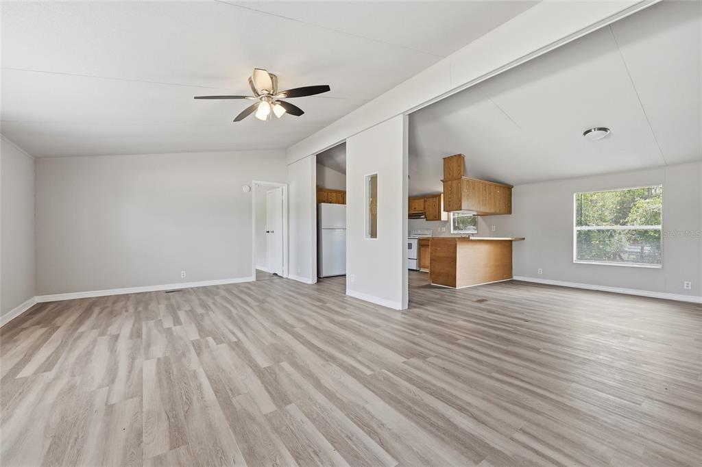 A living room with light wood-look flooring leads into a kitchen with wood cabinets — 350 ISHIE AVENUE, BRONSON, FL