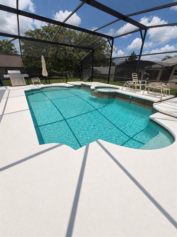 A screened-in swimming pool and spa with a concrete deck and a grill — 15849 MERCOTT COURT, CLERMONT, FL