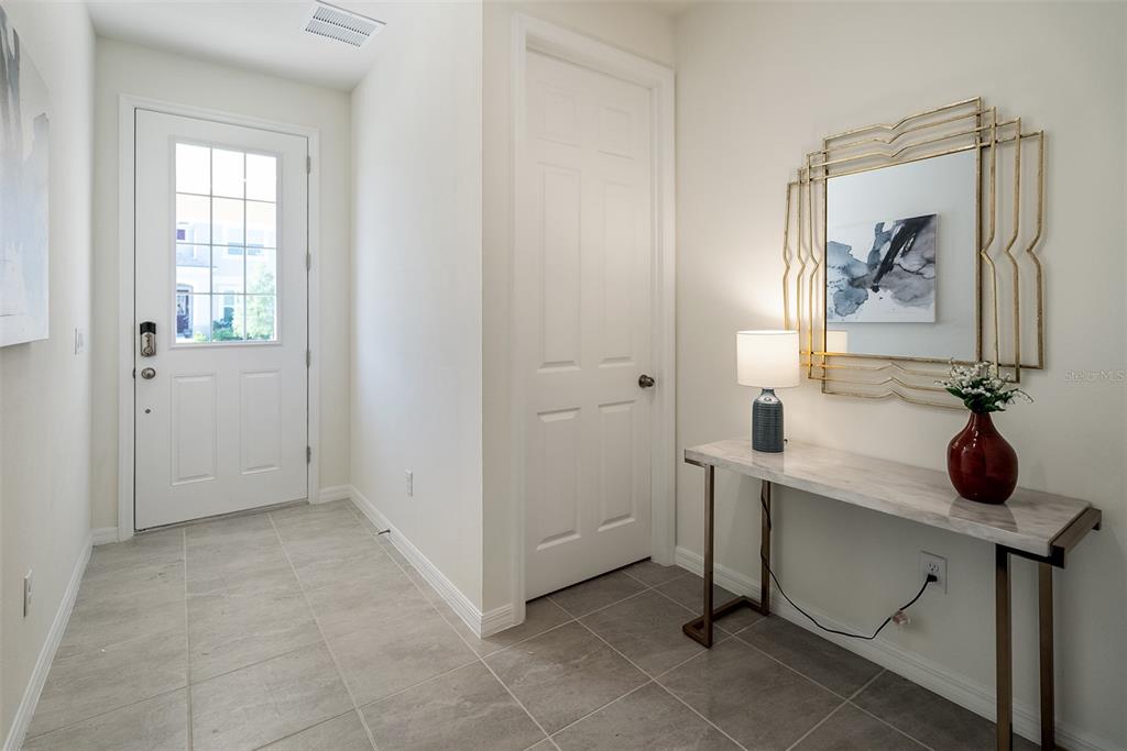 An entryway features a white front door, a closet door, and a marble-topped console table — 8953 COCONUT BREEZE DRIVE, KISSIMMEE, FL