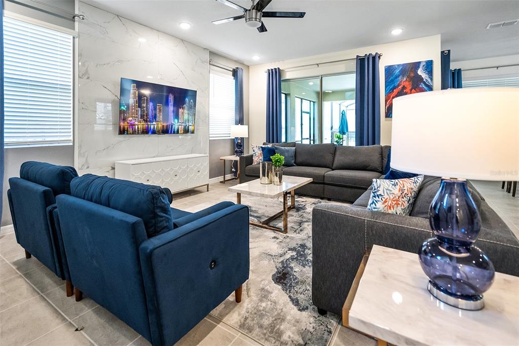 A living room features a marble accent wall, blue furniture, and a gray sectional sofa — 8953 COCONUT BREEZE DRIVE, KISSIMMEE, FL