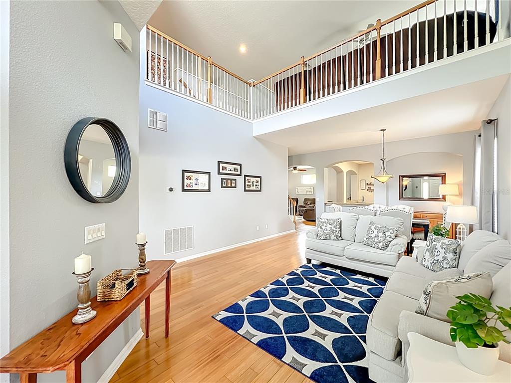 A living room with hardwood floors, a blue patterned rug, and a high vaulted ceiling — 949 PICKFAIR TERRACE, LAKE MARY, FL