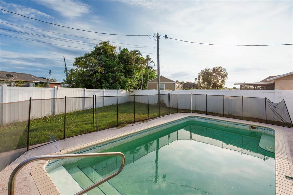 A backyard features a swimming pool with a safety fence and a white privacy fence — 2415 15TH STREET W, PALMETTO, FL