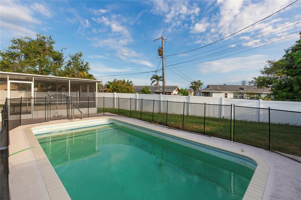 A backyard swimming pool with a black safety fence and a screened-in patio area — 2415 15TH STREET W, PALMETTO, FL
