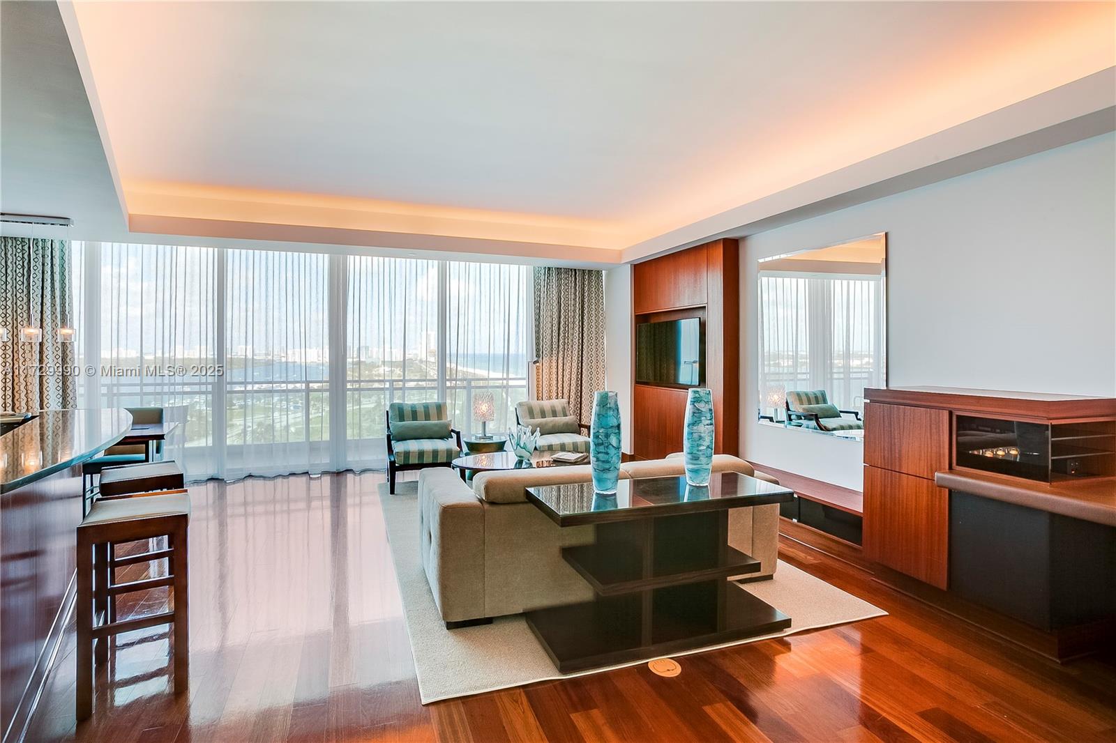 A modern living room features hardwood floors, a sofa, and floor-to-ceiling windows with ocean views — 10295 Collins Ave # 1613, Bal Harbour FL 33154, BAL HARBOUR, FL