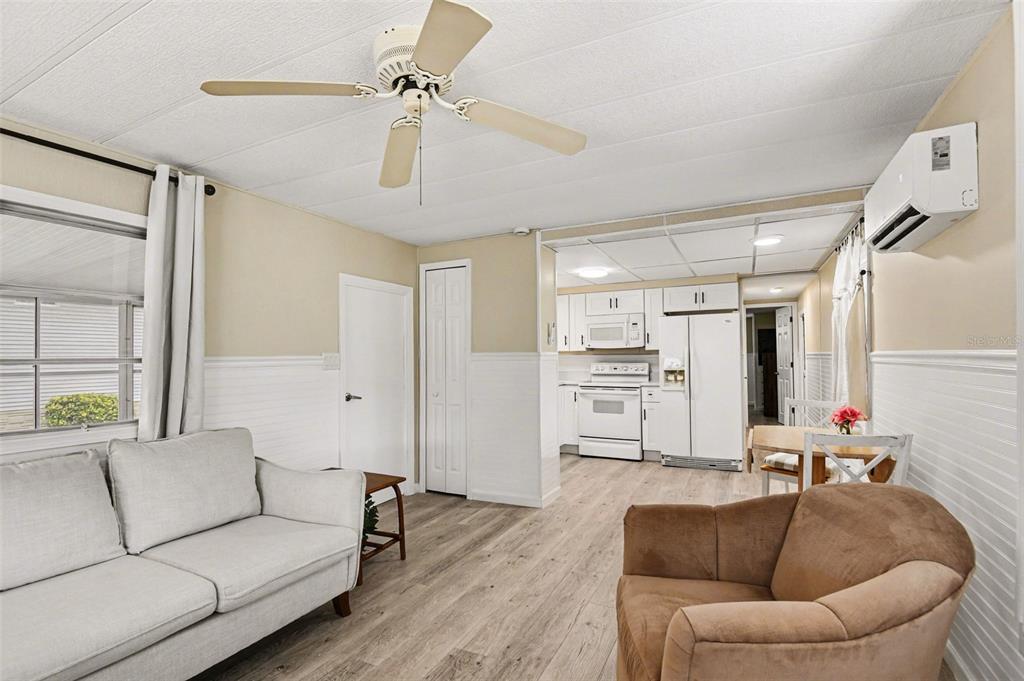 A living room with light wood flooring, a ceiling fan, and an open kitchen area — 20 HOLLAND DRIVE, PUNTA GORDA, FL