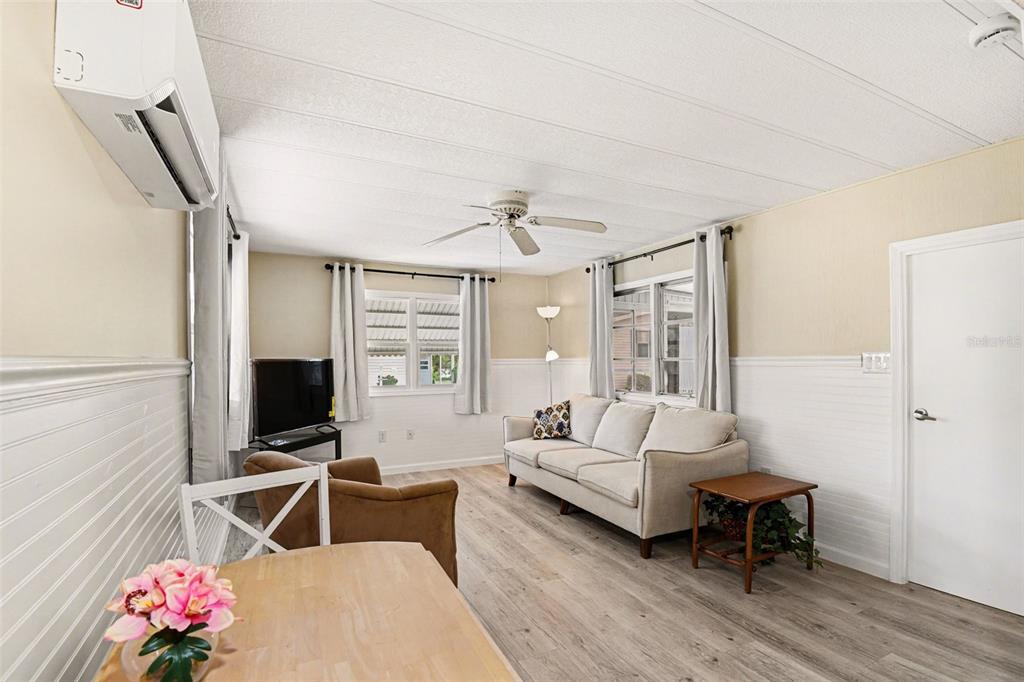 A living room with light wood flooring, a beige sofa, and a ceiling fan — 20 HOLLAND DRIVE, PUNTA GORDA, FL