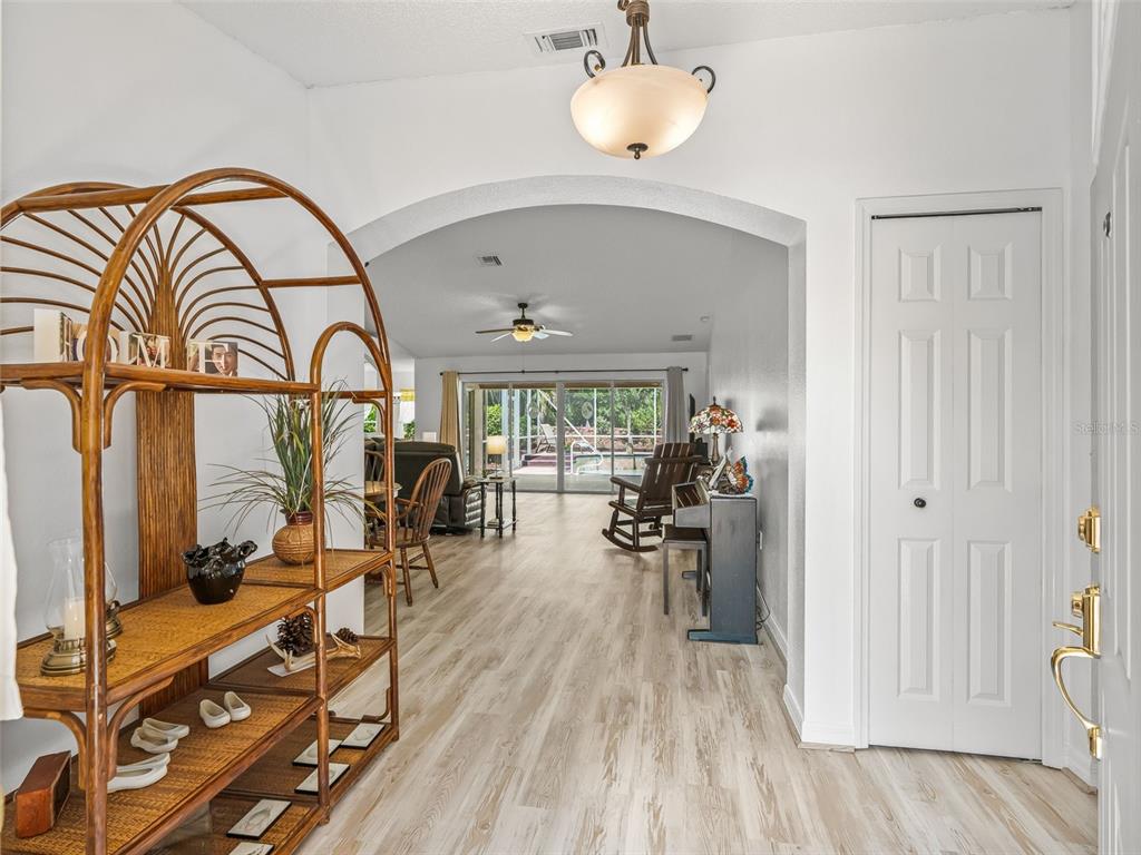 A foyer with a rattan shelf leads through an arched doorway into a living area — 15360 SW 15TH TERRACE ROAD, OCALA, FL
