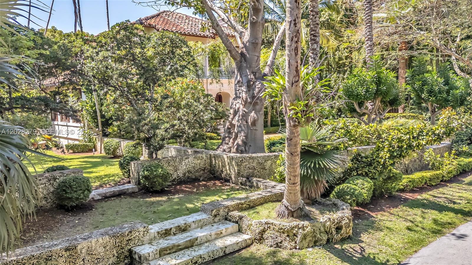 A stone staircase leads to a lush garden with mature trees and a Mediterranean-style house — 3462 N Moorings Way, Miami FL 33133, MIAMI, FL