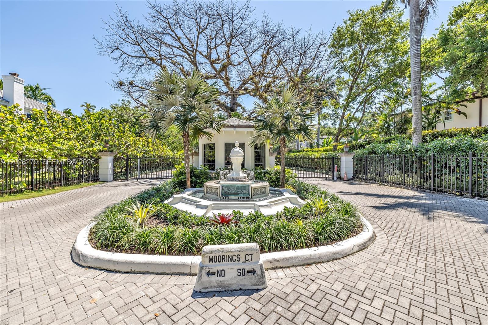 A stone fountain sits in the center of a paved driveway at a gated entrance — 3462 N Moorings Way, Miami FL 33133, MIAMI, FL